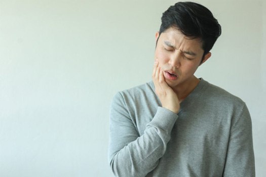 : a man holding his jaw due to discomfort