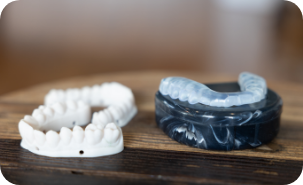 Clear occlusal splint tray next to a mold of a row of teeth